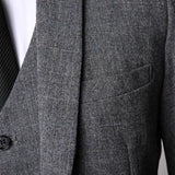 Grey tweed suit jacket showing herringbone fabric and chest pocket detail