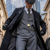 Man wearing a grey tweed three-piece suit with an overcoat and flat cap